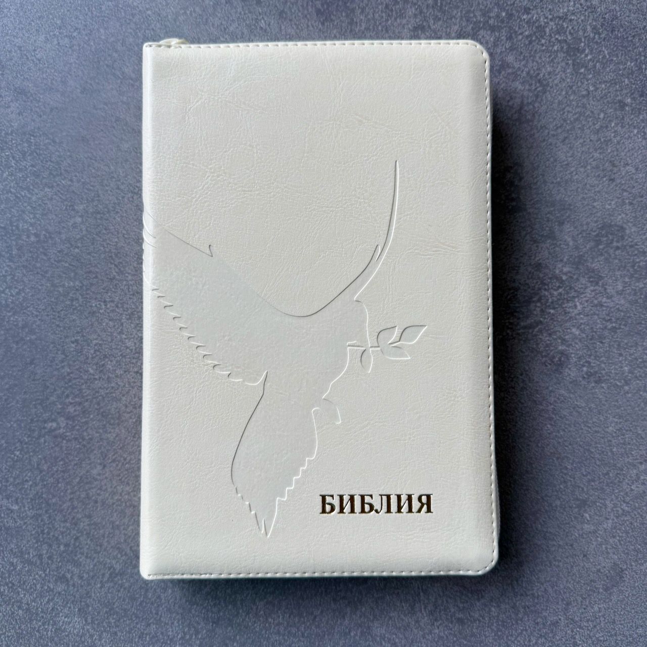 Дисконт 1. Серая черточка на лицевой обложке. Библия 055 zti код 26055-20 термо штамп "Голубь", переплет из эко кожи на молнии с индексами, цвет слоновая кость, средний формат, 143*220 мм