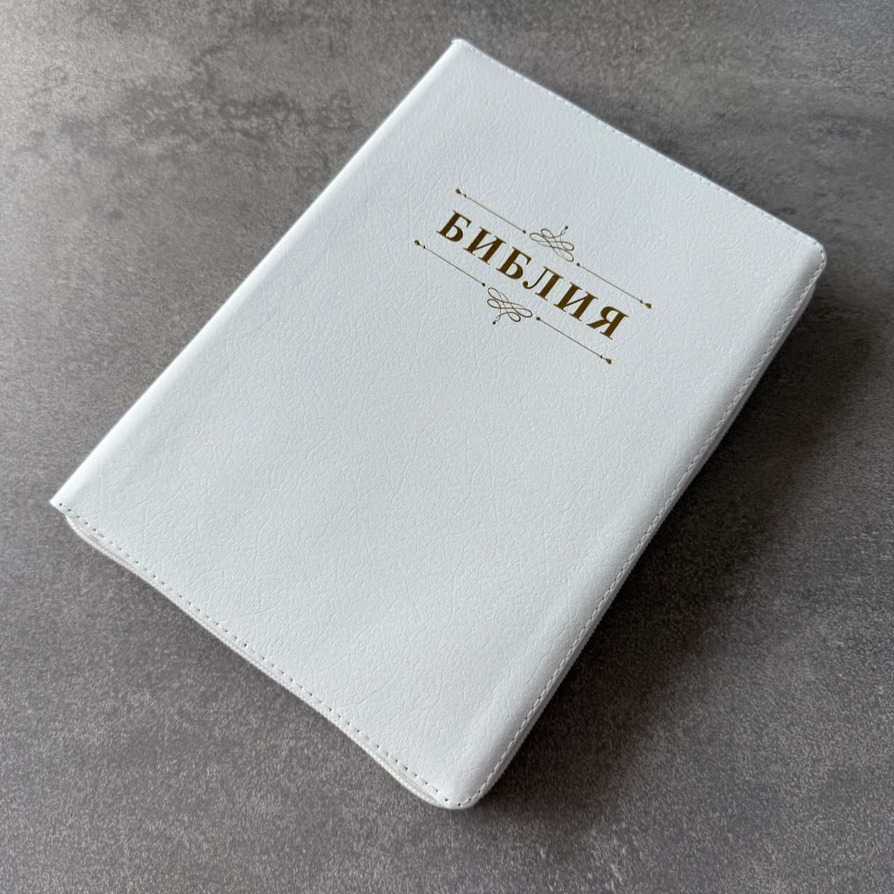 Дисконт. Бело-желтая полоска чуть выше центра спереди и сзади. Библия 076zti код 25076-16, дизайн "слово Библия", кожаный переплет на молнии с индексами, цвет белый пятнистый, размер 170x243 мм